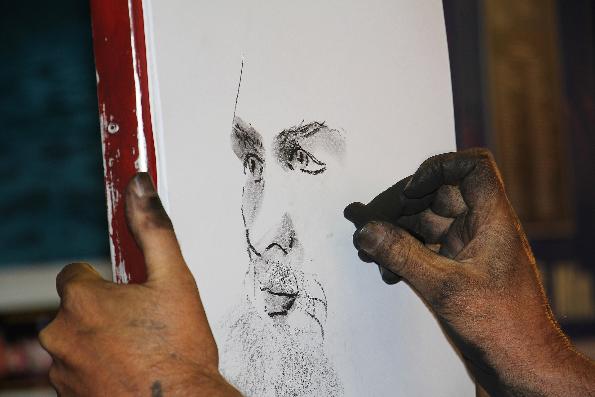 En person som tegner et portrett med kullstift