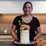 Bildeav Kristina med en ferdig kake, trukket med fondantlokk og dandert med blomster
