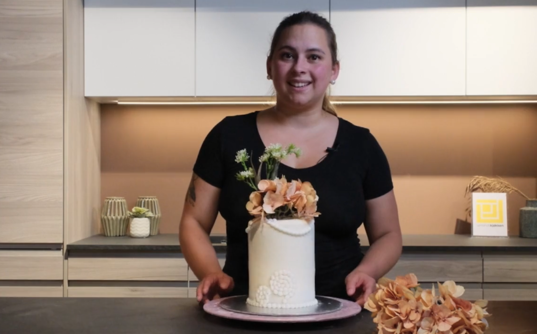 Bildeav Kristina med en ferdig kake, trukket med fondantlokk og dandert med blomster